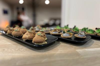Coucher de soleil rougeoyant derrière une rangée d'arbres, vu depuis une terrasse avec mobilier et voitures garées.