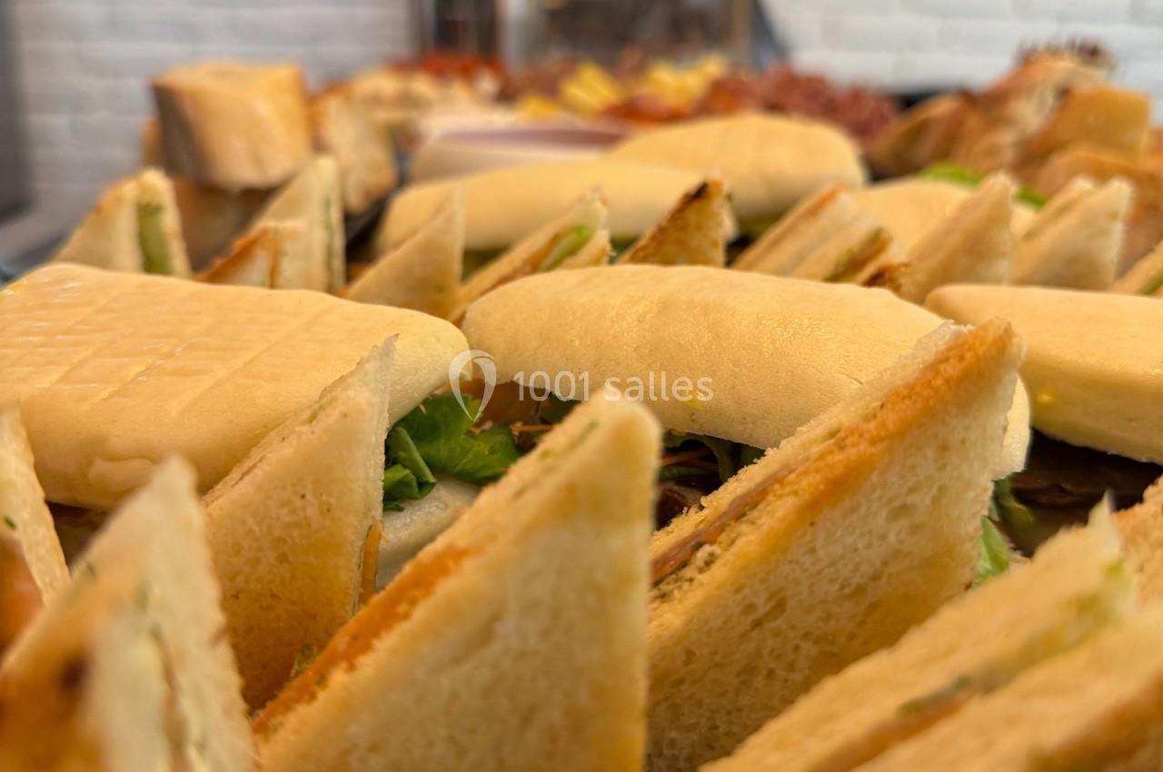 Assortiment de sandwichs triangulaires garnis, disposés sur un plateau dans un cadre lumineux.