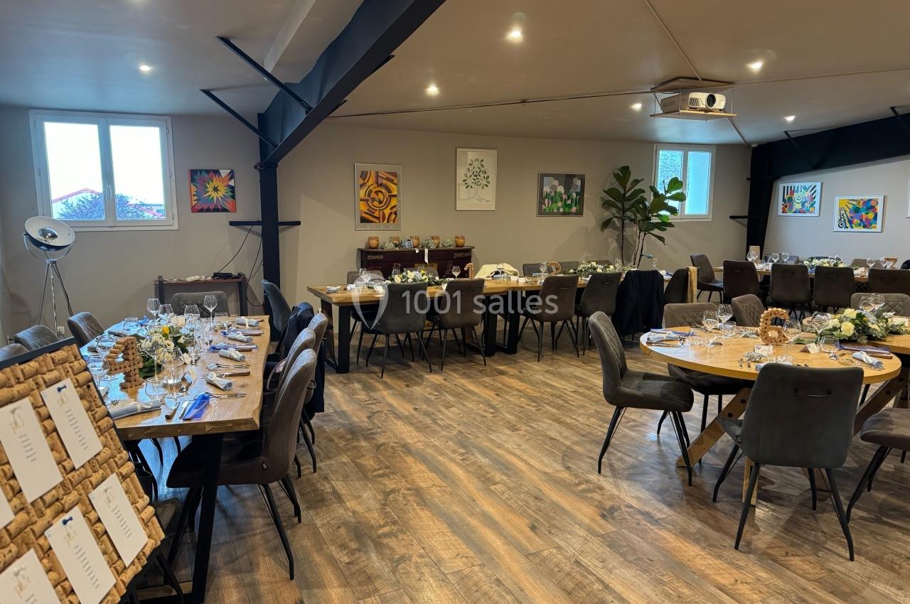 Salle de réception décorée avec des tables dressées, des chaises noires et des œuvres d'art accrochées aux murs.