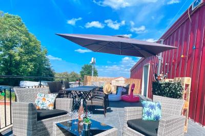 Coucher de soleil rougeoyant derrière une rangée d'arbres, vu depuis une terrasse avec mobilier et voitures garées.