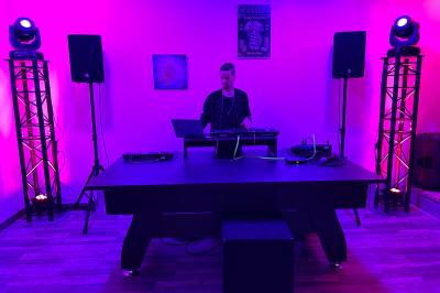 Coucher de soleil rougeoyant derrière une rangée d'arbres, vu depuis une terrasse avec mobilier et voitures garées.