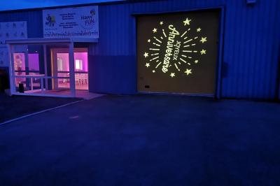 Miniature Location salle Chauny (Aisne) - Salle Happy Fun by Damaxx Events #1 Entrée d'un parking clôturé devant des bâtiments industriels avec des panneaux publicitaires sur la clôture.