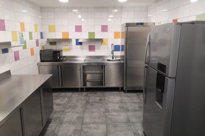 Cuisine professionnelle moderne avec équipements en inox, carrelage mural coloré et sol en carrelage gris.