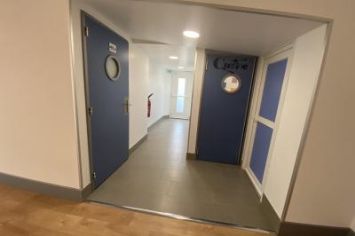 Cuisine professionnelle avec carrelage mural coloré, réfrigérateur, distributeur d'eau et équipements en inox.