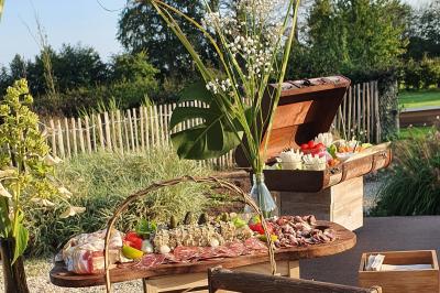 Plateau de légumes croquants, dips et charcuterie disposés sur une table en extérieur, avec des décorations végétales.