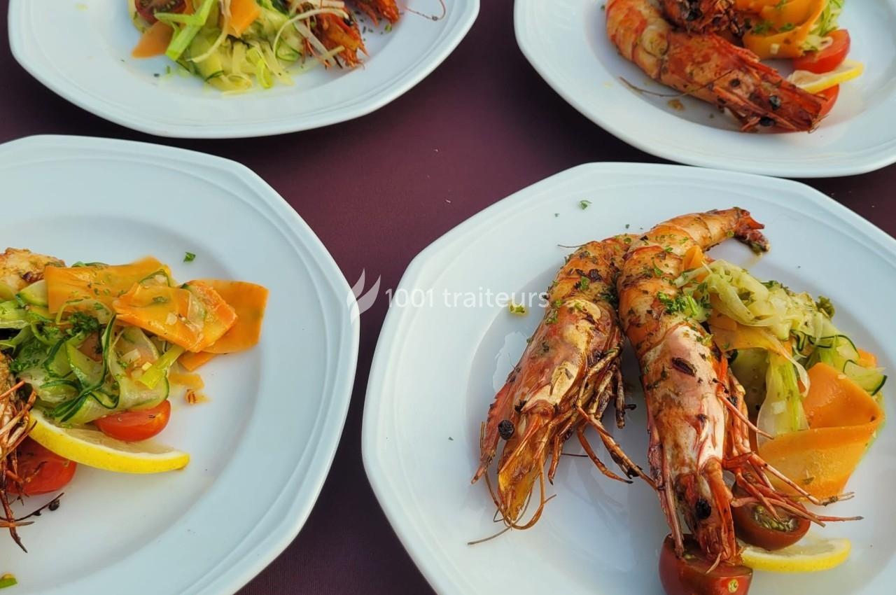 Assiettes de crevettes grillées accompagnées de légumes colorés et de tranches de citron, servies sur une nappe violette.