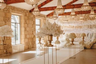 Une mariée en robe blanche et un marié en costume vert posent sur une voiture ancienne dans un cadre extérieur ensoleillé.