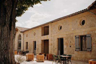 Une mariée en robe blanche et un marié en costume vert posent sur une voiture ancienne dans un cadre extérieur ensoleillé.