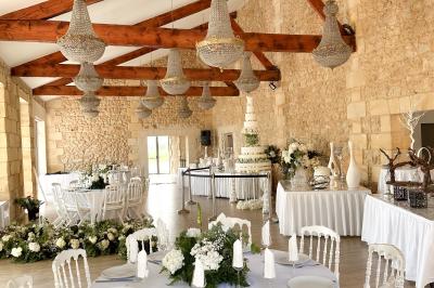 Une mariée en robe blanche et un marié en costume vert posent sur une voiture ancienne dans un cadre extérieur ensoleillé.