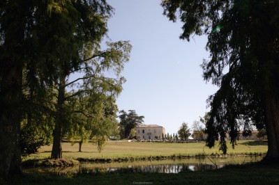 Jardin avec plantes méditerranéennes, éclairé la nuit, devant des bâtiments en pierre et des arbres taillés.