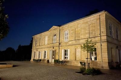 Une mariée en robe blanche et un marié en costume vert posent sur une voiture ancienne dans un cadre extérieur ensoleillé.