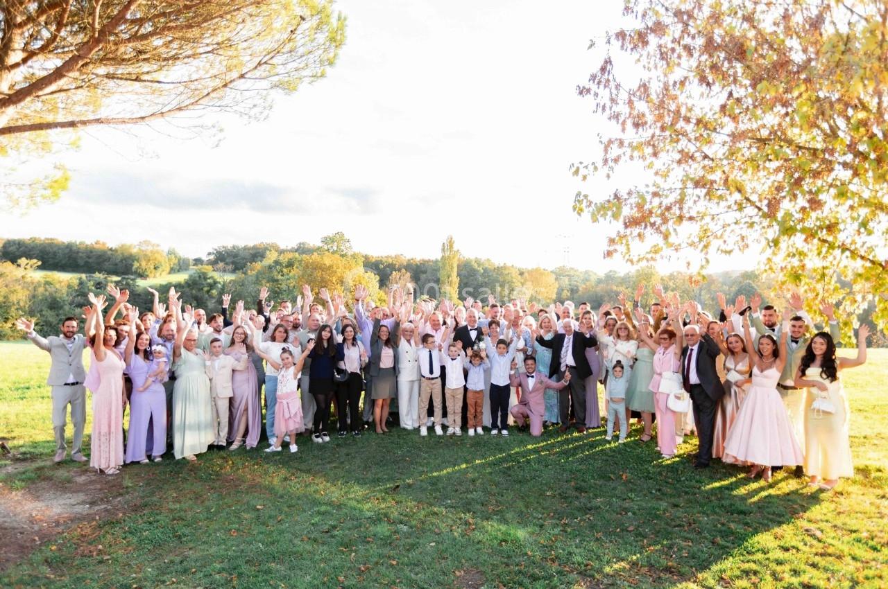 Groupe de personnes posant en plein air dans un cadre naturel, sous un ciel clair et entouré d'arbres.