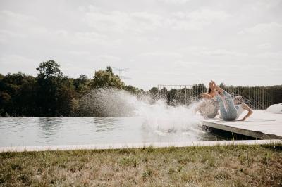 Une mariée en robe blanche et un marié en costume vert posent sur une voiture ancienne dans un cadre extérieur ensoleillé.