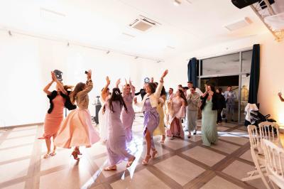 Une mariée en robe blanche et un marié en costume vert posent sur une voiture ancienne dans un cadre extérieur ensoleillé.