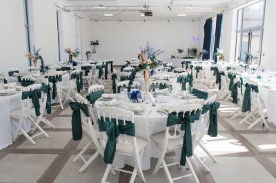 Une mariée en robe blanche et un marié en costume vert posent sur une voiture ancienne dans un cadre extérieur ensoleillé.