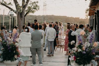 Une mariée en robe blanche et un marié en costume vert posent sur une voiture ancienne dans un cadre extérieur ensoleillé.