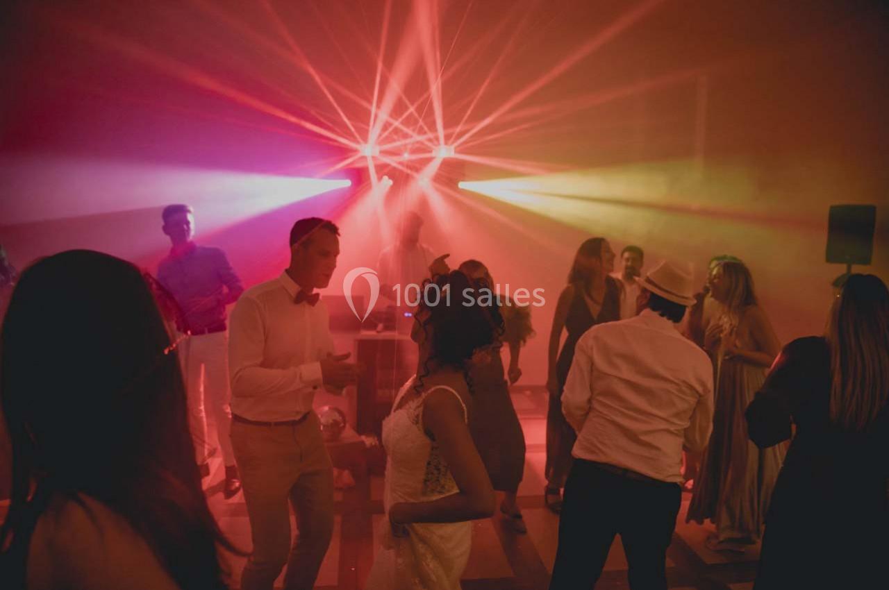 Des personnes dansent sous des lumières colorées dans une ambiance festive et tamisée.