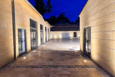 Une mariée en robe blanche et un marié en costume vert posent sur une voiture ancienne dans un cadre extérieur ensoleillé.