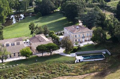 Une mariée en robe blanche et un marié en costume vert posent sur une voiture ancienne dans un cadre extérieur ensoleillé.