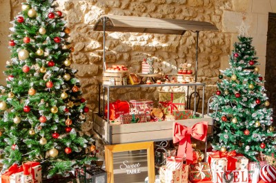 Miniature Arbre de Noël entreprise - ©flora-lauriola Façade d'un bâtiment en pierre avec grandes baies vitrées illuminées par des lumières roses à la tombée de la nuit.