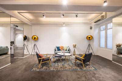 Salle lumineuse avec verrière, murs blancs, sol clair et mobilier minimaliste comprenant une table basse et un fauteuil.