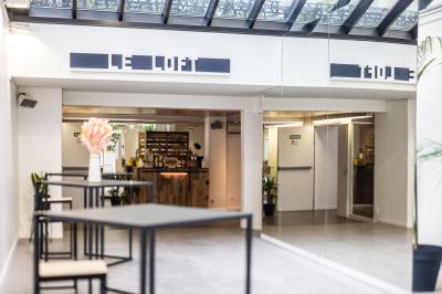 Salle lumineuse avec verrière, murs blancs, sol clair et mobilier minimaliste comprenant une table basse et un fauteuil.