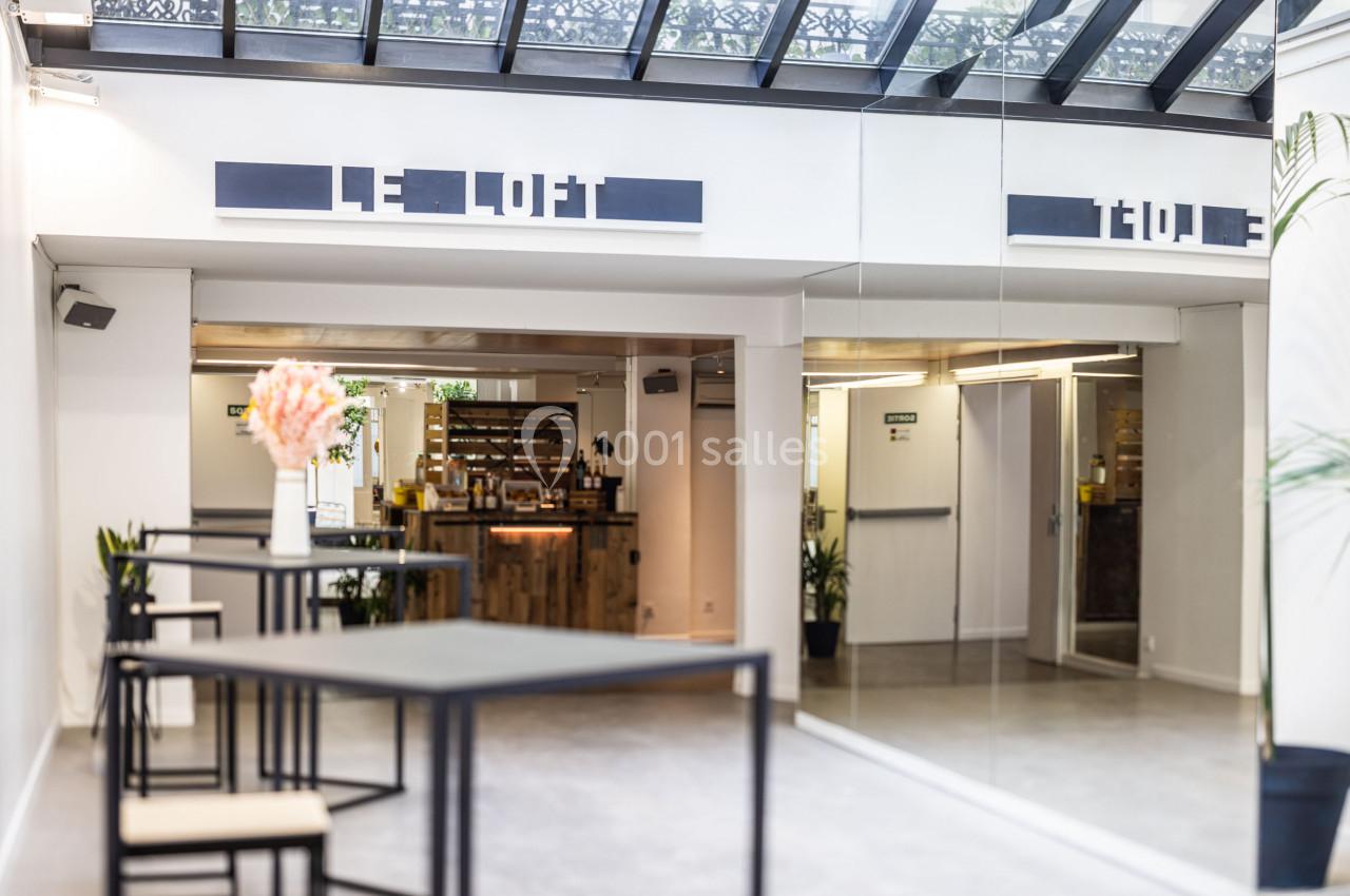 Espace intérieur lumineux avec verrière, mobilier moderne et comptoir en bois dans un lieu nommé ’Le Loft’.