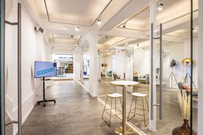 Salle lumineuse avec verrière, murs blancs, sol clair et mobilier minimaliste comprenant une table basse et un fauteuil.