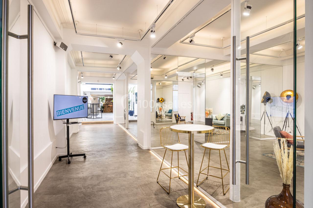 Espace lumineux avec murs blancs, mobilier minimaliste, écran affichant ’Bienvenue’ et décorations modernes.