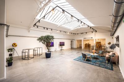 Salle lumineuse avec verrière, murs blancs, sol clair et mobilier minimaliste comprenant une table basse et un fauteuil.