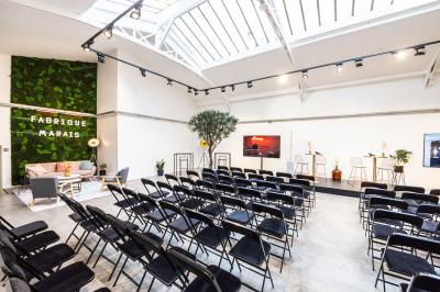 Salle lumineuse avec verrière, murs blancs, sol clair et mobilier minimaliste comprenant une table basse et un fauteuil.