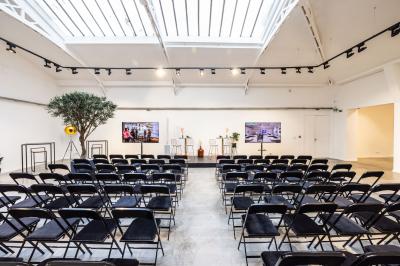 Salle lumineuse avec verrière, murs blancs, sol clair et mobilier minimaliste comprenant une table basse et un fauteuil.