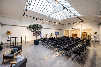 Salle lumineuse avec verrière, murs blancs, sol clair et mobilier minimaliste comprenant une table basse et un fauteuil.