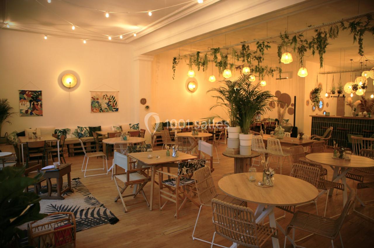 Salle de restaurant lumineuse avec décoration végétale, mobilier en bois et ambiance chaleureuse.