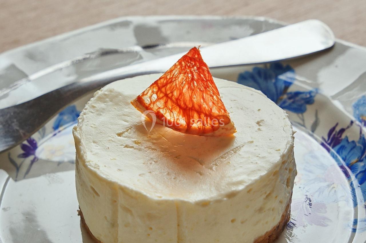 Gâteau au fromage individuel sur une assiette fleurie, garni d'un segment d'orange sanguine.