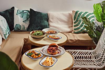 Saumon grillé garni de pousses, accompagné de kimchi, servi dans une assiette en céramique sur une nappe rayée.