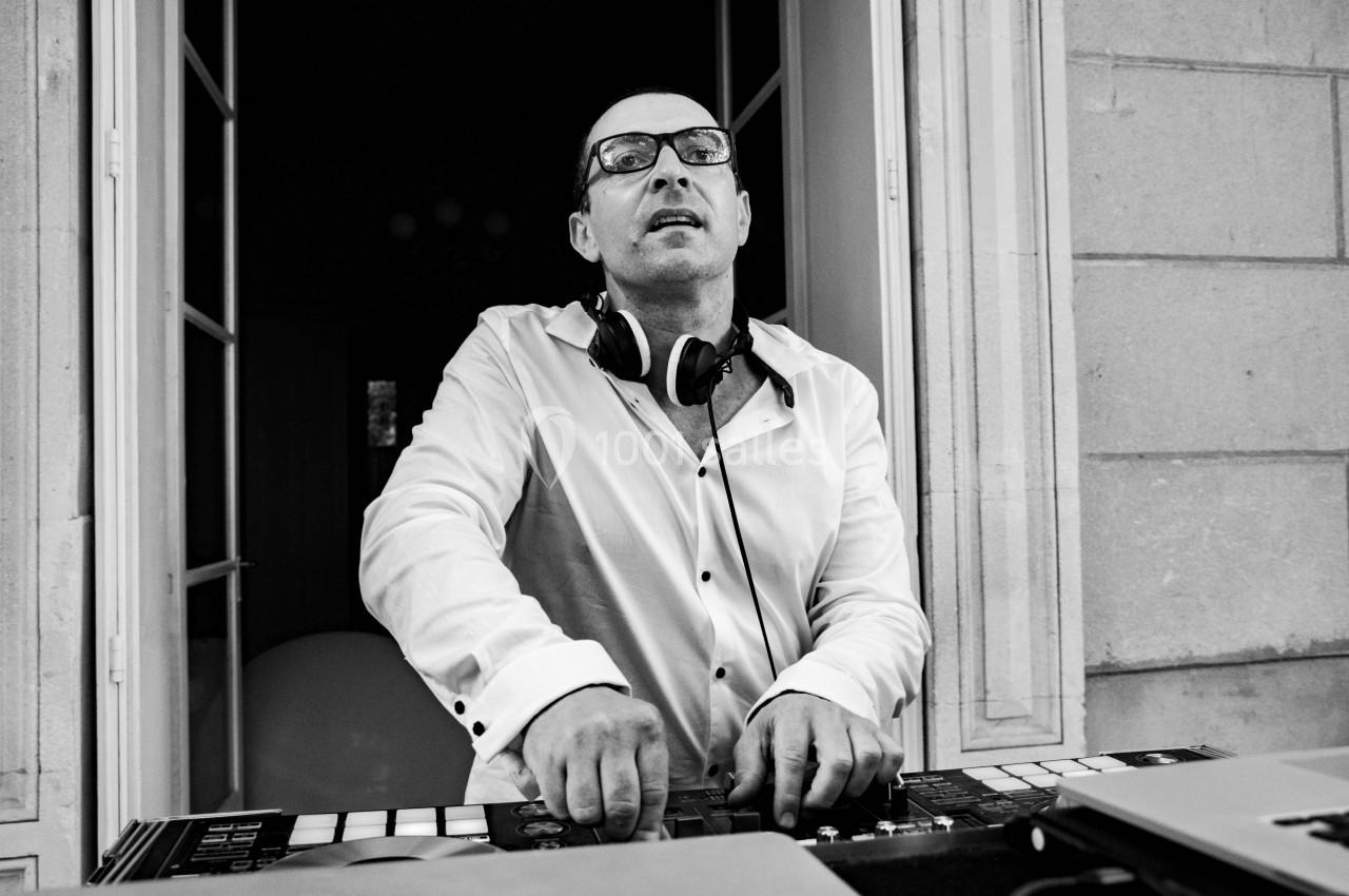 Un homme portant des lunettes et un casque audio mixe de la musique sur une table de mixage dans un cadre intérieur.