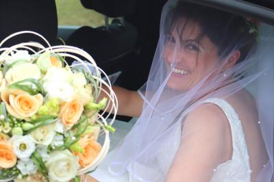 Femme en peignoir blanc se maquillant devant un miroir, ses cheveux ornés de petites fleurs blanches.