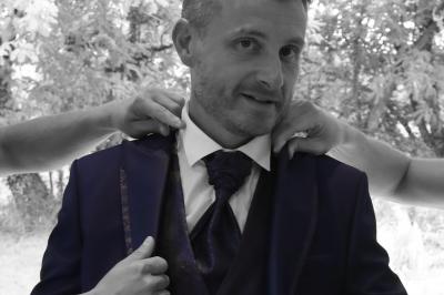 Femme en peignoir blanc se maquillant devant un miroir, ses cheveux ornés de petites fleurs blanches.