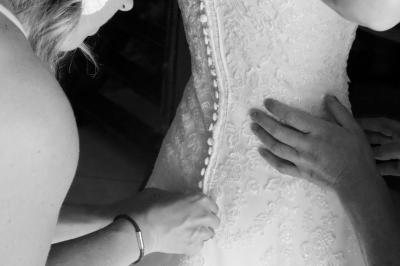 Femme en peignoir blanc se maquillant devant un miroir, ses cheveux ornés de petites fleurs blanches.