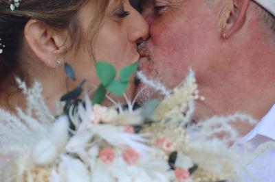 Femme en peignoir blanc se maquillant devant un miroir, ses cheveux ornés de petites fleurs blanches.