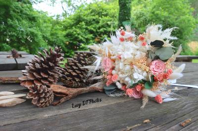 Femme en peignoir blanc se maquillant devant un miroir, ses cheveux ornés de petites fleurs blanches.