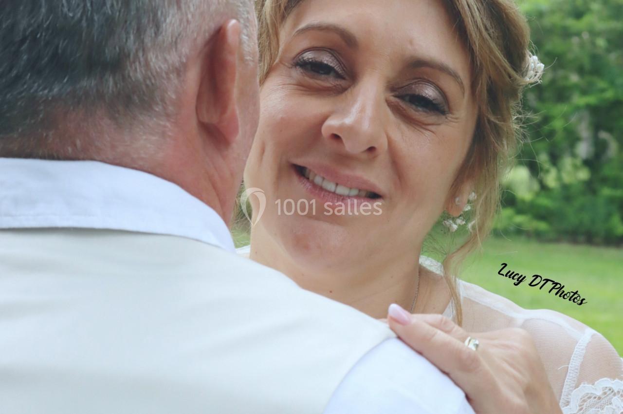 Une femme souriante regarde un homme de dos, dans un cadre extérieur verdoyant.