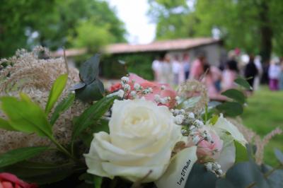 Femme en peignoir blanc se maquillant devant un miroir, ses cheveux ornés de petites fleurs blanches.