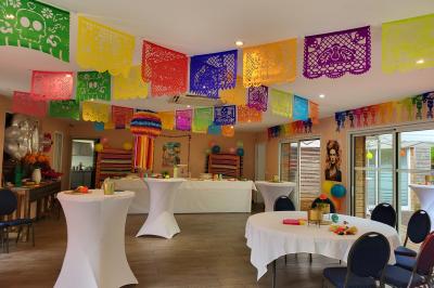 Musiciens mariachi jouant de la trompette, de la guitare et du violon dans une salle décorée de couleurs vives et de…