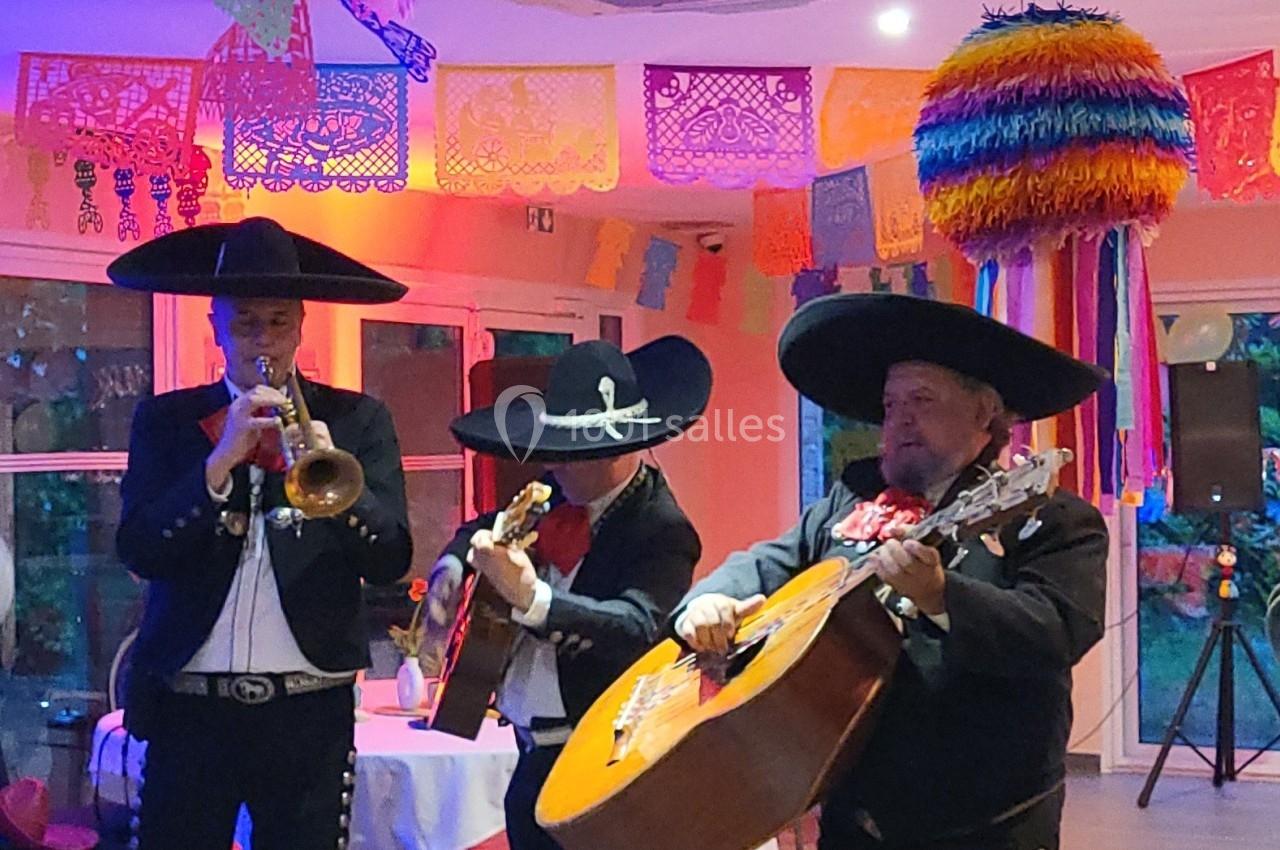 Musiciens mariachi jouant de la trompette, de la guitare et du violon dans une salle décorée de couleurs vives et de…