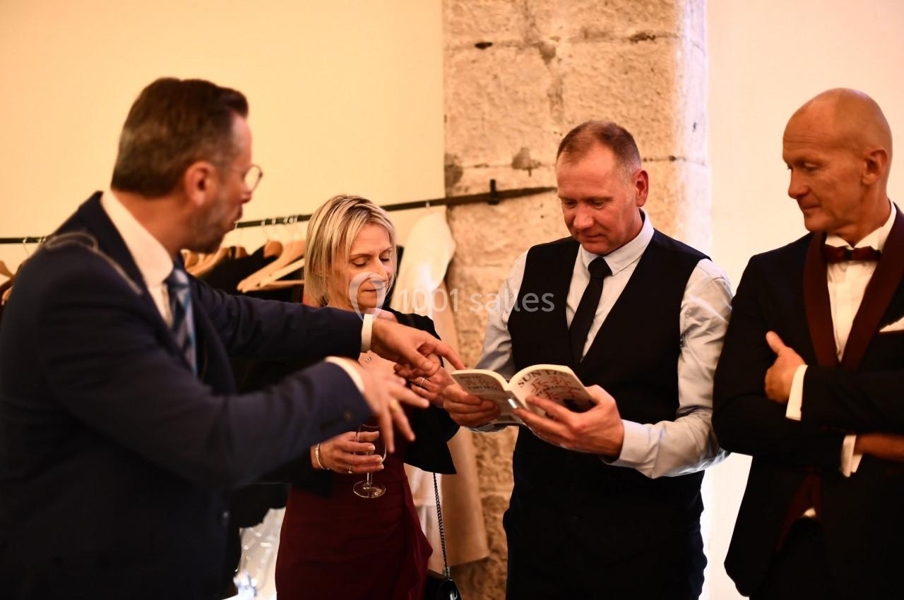 Un groupe de personnes en tenue élégante échange autour d'un livre dans un espace intérieur.