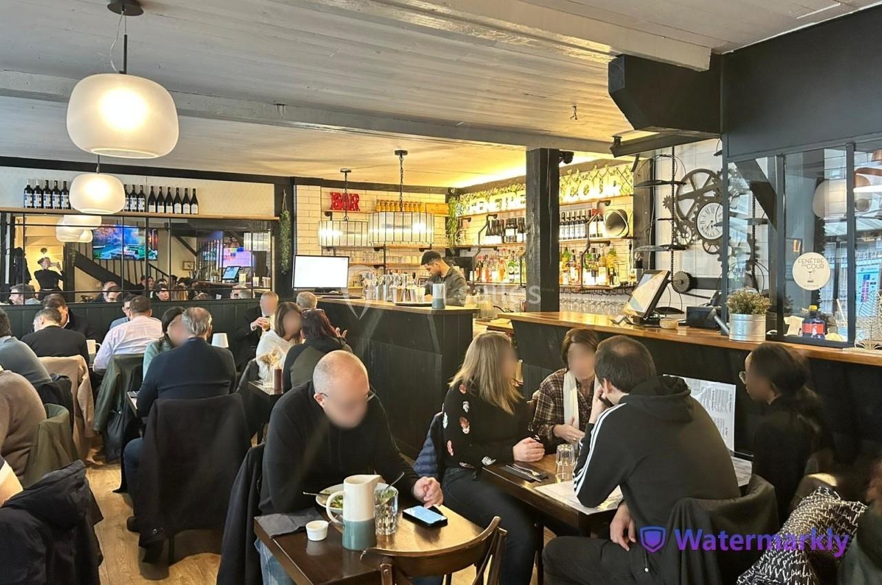 Intérieur d'un café animé avec des clients attablés et un comptoir en arrière-plan.