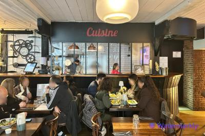 Intérieur d'un café animé avec des clients attablés et un comptoir en arrière-plan.