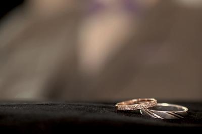 Deux alliances en métal, dont une ornée de petits diamants, posées sur un tissu noir avec un fond flou.